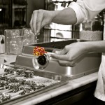 A black and white photo of Parker, the Chocolatier, decorating the colourful Oreo Chocolate Cookie Pop.