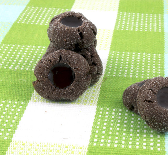 A photo of stacked chocolate thumbprints on a green patterned placemat.