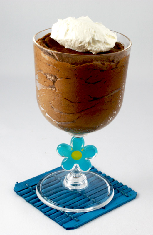 Gordon Ramsay Four-Minute Chocolate Mousse A close up photo of a chocolate mousse in a clear wine plastic tumbler on a blue wooden coaster.