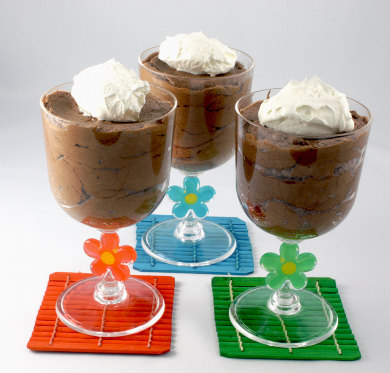 Gordon Ramsay Four-Minute Chocolate Mousse A photo of chocolate mousse in three clear plastic wine tumblers on three coloured (green, orange and blue) wooden coasters.