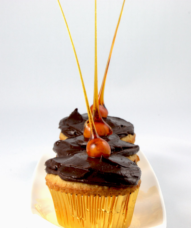 Candied-Hazelnut Cupcakes A close up photo of 3 candied-hazelnut cupcakes on a white dish.