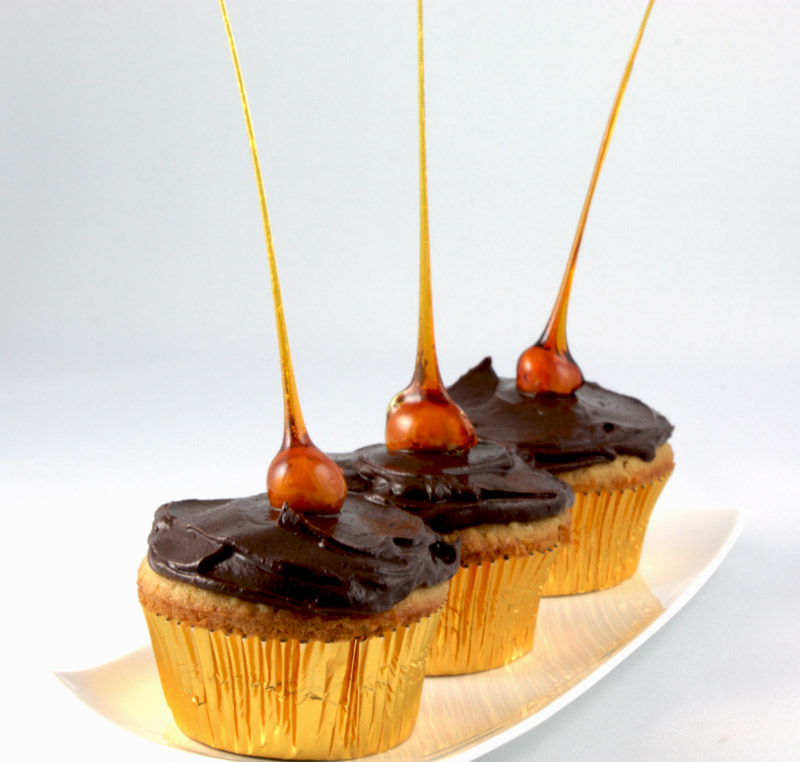 Candied-Hazelnut Cupcakes A close up photo of 3 candied-hazelnut cupcakes on a white plate.