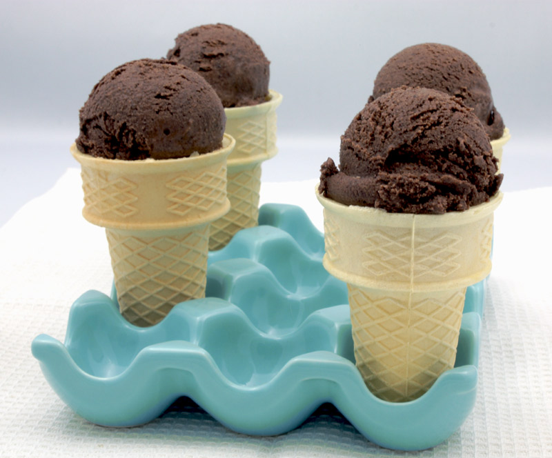 Ben & Jerry's Chocolate Ice Cream a photo of 4 ice cream comes of chocolate ice cream in a blue egg tray on a white waffle tea towel.