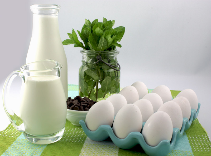 Mint Chocolate Chip Ice Cream A photo of mint chocolate chip ice cream mise en place, which includes eggs, milk, cream, fresh mint and chocolate chips on a green placemat.