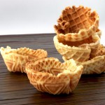 A photo of 5 waffle cups on a wooden placemat.