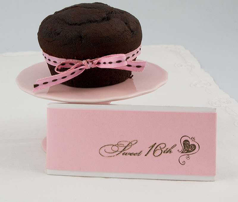 Martha Stewart's Black Forest Cupcakes A photo of a black forest cupcake with a pink ribbon on a mini pink cake stand with a card saying "Sweet 16th" placed on a white napkin.