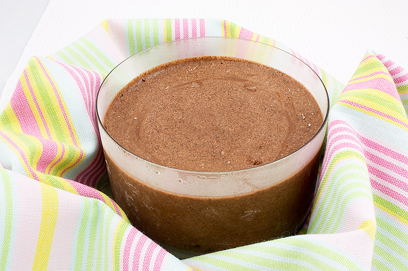 A photo of a large bowl of double chocolate brownie semifreddo nestled in a crumpled, multi-coloured tea towel.