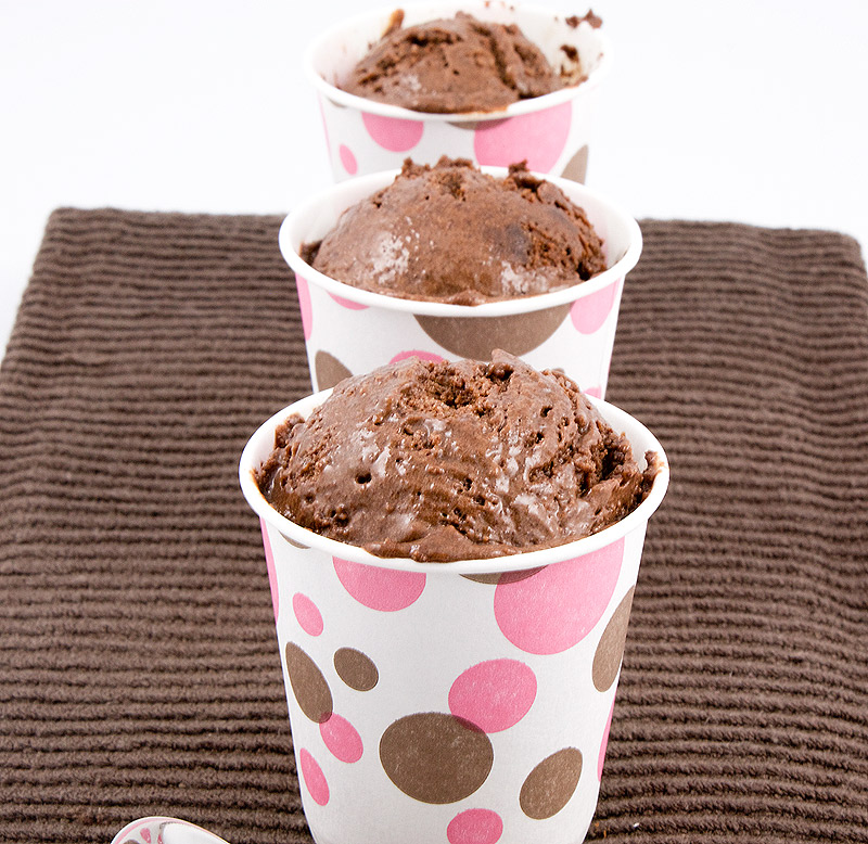 A photo of 3 double chocolate brownie semifreddo desserts, served in pink and brown polka dotted cups, lined up in a row placed on a brown tea towel.