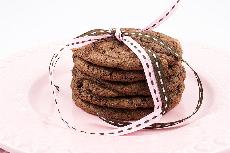 double-chocolate chunk cookies, Martha Stewart's recipe for double-chocolate chunk cookies, easy recipe for double chocolate chunk cookies A close up photo of a stack of double-chocolate chunk cookies tied with 2 ribbons, one pink and one brown, placed on 2 pink dishes.