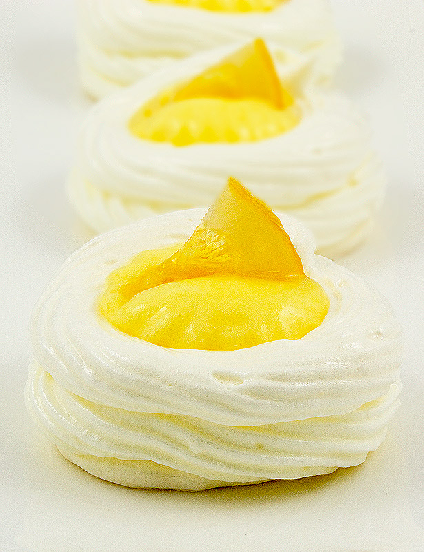lemon curd meringue nests, meringue nests, meringue cups, easy lemon curd A photo of 3 lemon curd meringue nests garnished with candied lemon slices on a white plate.