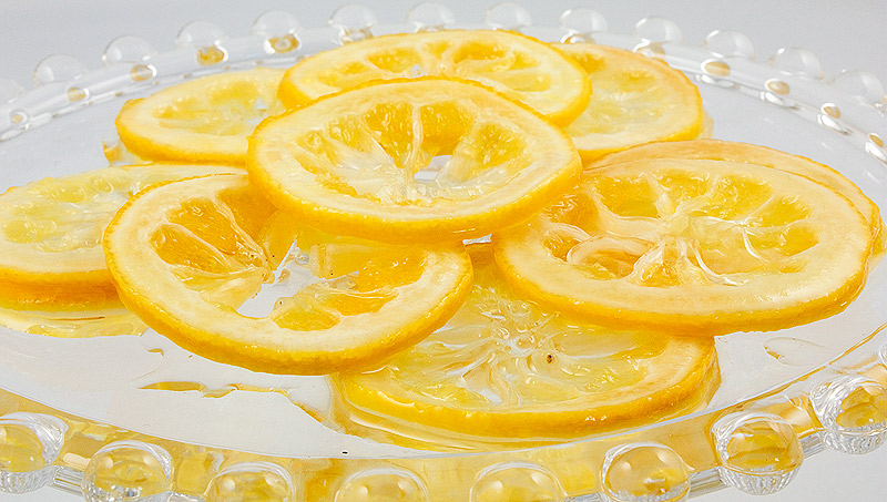 candied lemon slices, sugared lemon peel, sugared lemon slices, garnishes for lemon curd meringue nests A photo of candied lemon slices on a glass cake stand.