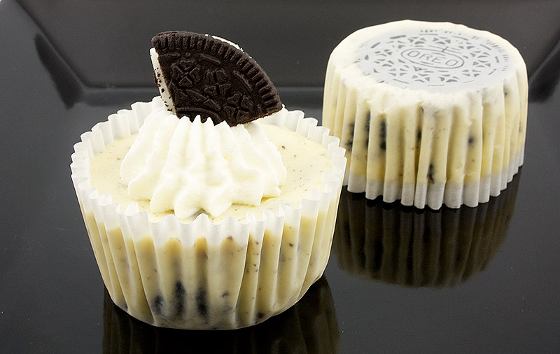 Oreo cookies and cream cheesecake cupcakes, Martha Stewart's cupcake recipes, cookies and cream cheesecakes recipe A photo of 2 Oreo cookies and cream cheesecakes, 1 with whipped cream and an Oreo cookie, and the other flipped upside down with Oreo cookie side showing, placed on a black plate.