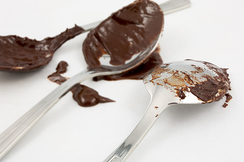 Donna Hay's recipe for chocolate mud cake, Donna Hay's recipe for dark chocolate ganache frosting, Donna Hay's recipe for sweet glazed cherries A photo of 3 spoons partially coated in dark chocolate ganache.
