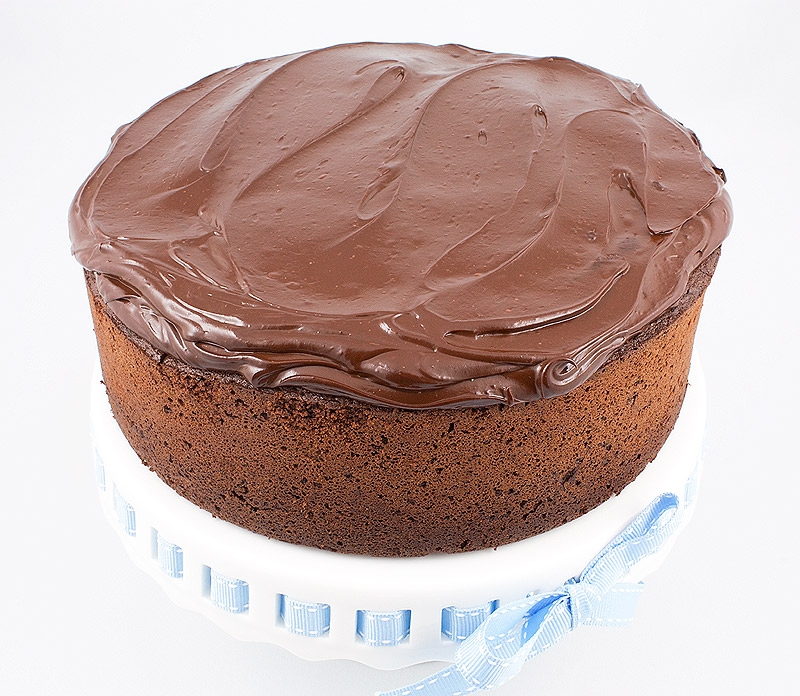 Donna Hay's recipe for chocolate mud cake, Donna Hay's recipe for dark chocolate ganache frosting, Donna Hay's recipe for sweet glazed cherries A close up photo of chocolate mud cake with dark chocolate ganache frosting.