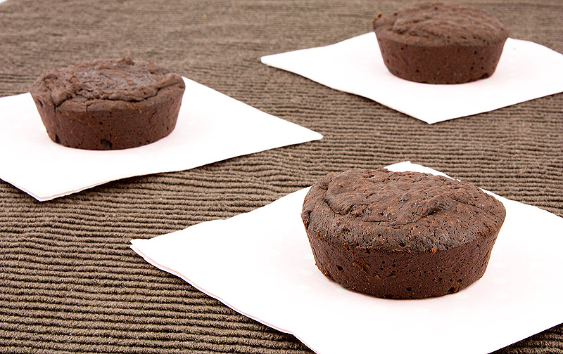 A photo of 3 flourless chocolate cakes place on small pink polka dot napkins in random order on a chocolate brown tea towel.