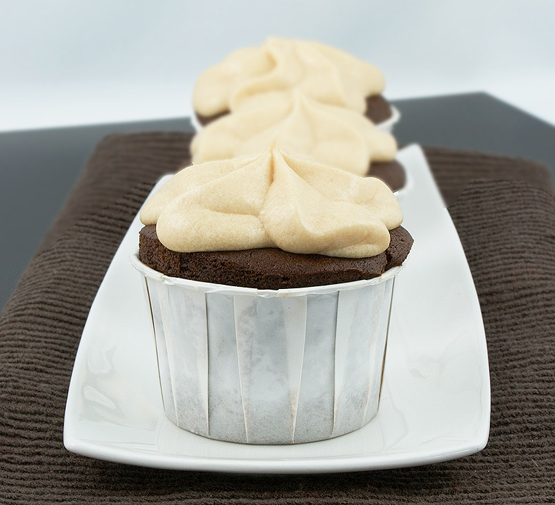 caramel buttercream frosting, quick and easy cupcakes, boozy cupcakes A photo of 3 Caramilk Cream-Vodka Cooler Cupcakes with Caramel Buttercream Frosting, placed in a row on a white rectangular plate.