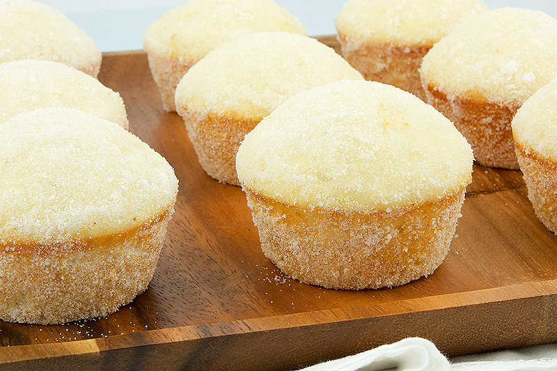 sugar donut muffin recipe, easy chocolate muffin recipe A close up photo of sugar donut muffins on a brown wooden plate.