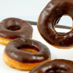 how to make doughnuts at home, doughnut recipe, chocolate doughnut glaze A photo of 4 chocolate glazed doughnuts with one suspended in the air.