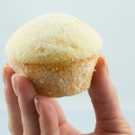 A photo of a person's hand holding a sugar donut muffin.