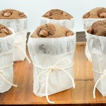 A photo of Nigella Lawson's double chocolate chip muffins wrapped in parchment paper and tied with string and placed on a wooden tray.