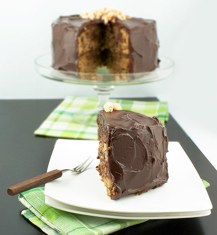 easy chocolate desserts, desserts with photos, quick and easy desserts A photo of a Banana Cake with Mocha Frosting and Salted Candied Peanuts pictured on a cake stand with a piece removed and pictured on a white plate.