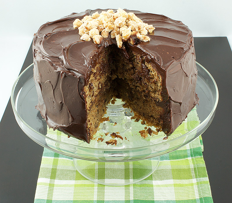banana bread recipes, easy banana bread recipe, simple mocha ganache recipe A photo taken looking down on a Banana Cake with Mocha Frosting and Salted Candied Peanuts with a piece removed and displayed on a glass cake stand.