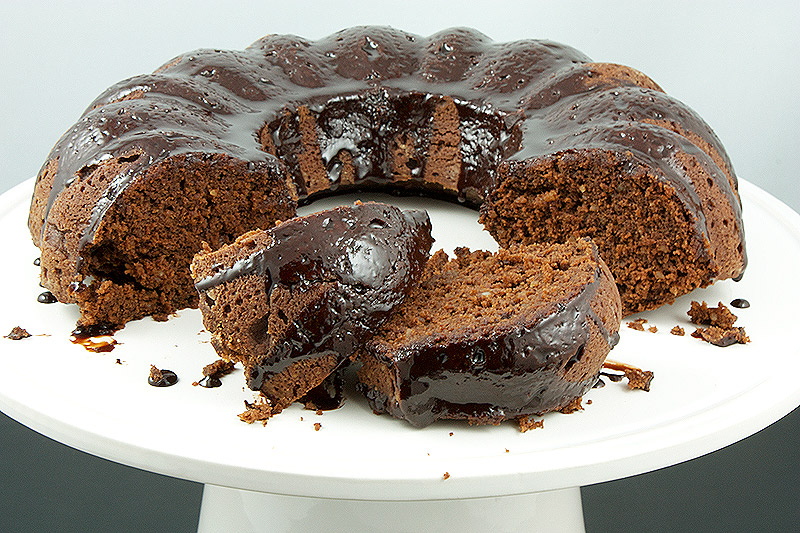 bundt cake glaze, quick and easy desserts, easy chocolate desserts, desserts with photos A photo of Donna Hay's Chocolate Bundt Cake with Butterscotch Cocoa Glaze displayed on a white cake stand with a couple of pieces cut and displayed on there sides.