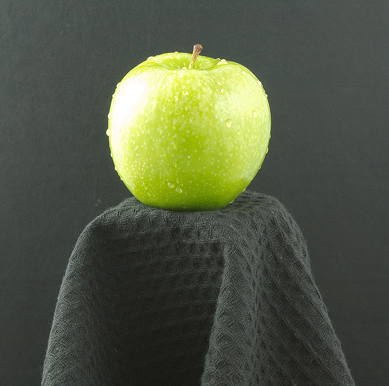 Green Apple A photo of a green apple placed on a pedestal.