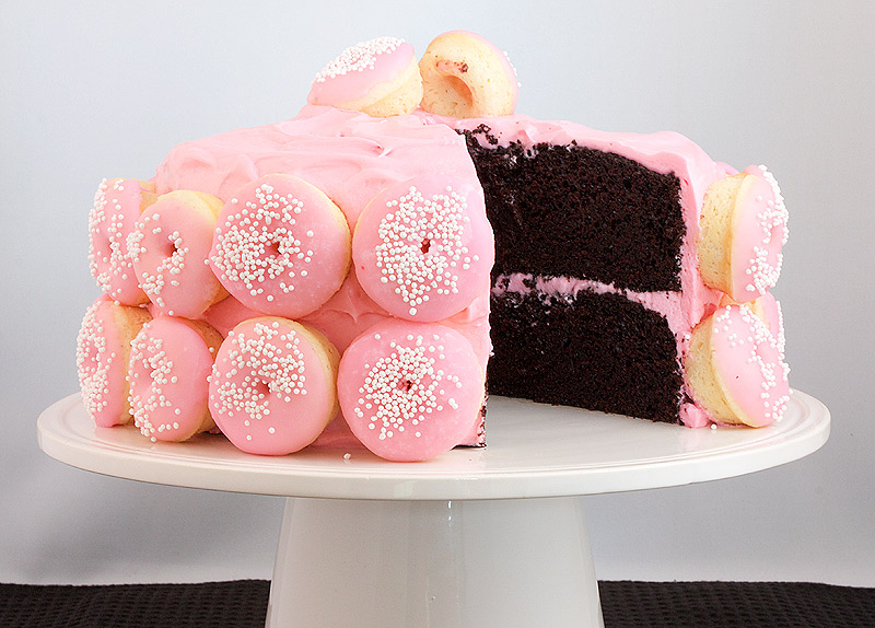 chocolate birthday cake, easy chocolate cake recipe, desserts with photos, white chocolate cream cheese icing A photo taken of a Chocolate Layer Cake with White Chocolate Cream Cheese Frosting decorated with mini Baked White Chocolate Cake Doughnuts with pink Vanilla Glaze and sprinkled with white nonpareils.