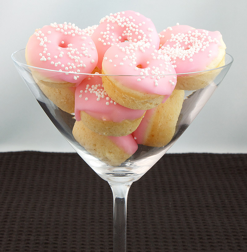Baked White Chocolate Cake Doughnuts with Pink Vanilla Doughnut Glaze A photo of Baked White Chocolate Cake Doughnuts in a clear martini glass.