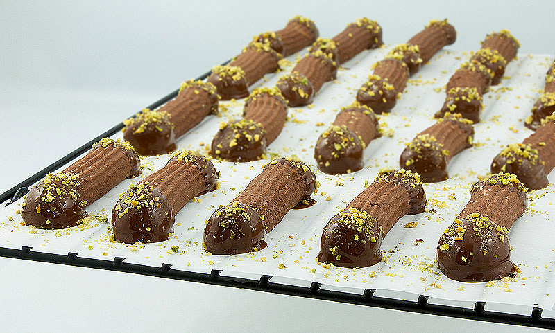 Chocolate-Hazelnut Spritz Cookies A photo of Chocolate-Hazelnut Spritz Cookies dipped in chocolate and sprinkled with pistachio crumb.