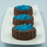 A photo of 3 pieces of Chocolate Marshmallow Fudge decorated with crushed blue candy canes.