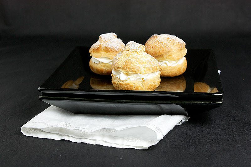 recipe profiteroles, hot fudge sauce recipe, chocolate sauce recipe A photo of 3 Profiteroles with Chantilly Cream on a black plate.