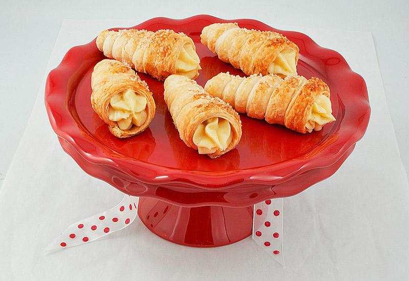 Italian Pastries A photo of Italian Pastries, pastry horns filled with Italian pastry cream, displayed on a red cake stand.