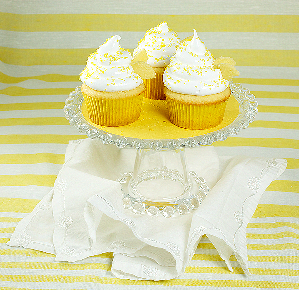 Honey-Kissed Yellow Cupcakes with Meringue Icing A photo of 3 Honey-Kissed Yellow Cupcakes with Meringue Icing displayed on a glass cake stand.