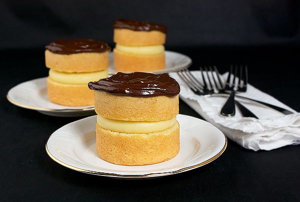 Boston Cream Pies A photo of three Mini Boston Cream Pie desserts served on white dessert plates.