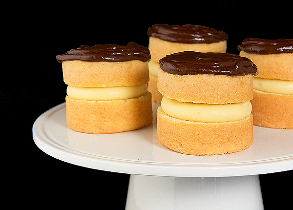boston cream pie recipe, pastry cream, creme patisserie A photo of four mini Boston Cream cakes displayed on a white cake stand.