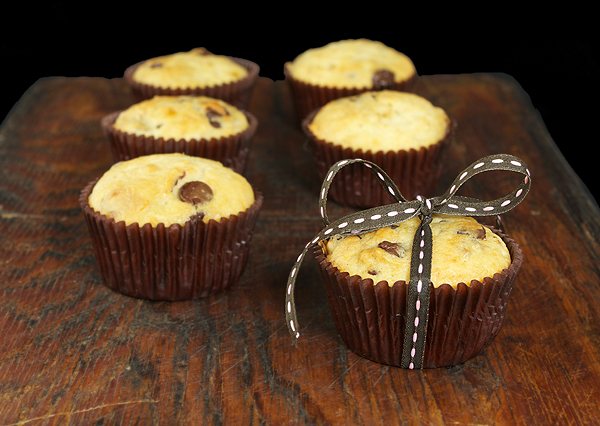 Chocolate Chip Banana Muffins A photo of 6 standard-sized Chocolate Chip Banana Muffins arranged in two rows of three with brown and pink ribbon tied in a bow on one muffin.