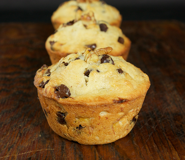 recipe for muffins, recipe for banana muffins, bananas muffins A photo of 3 Jumbo Banana Muffins arranged in a row (one behind the other) on a dark wooden board.