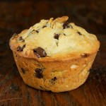 A photo of a jumbo Chocolate Chip Banana Muffin displayed on a wooden board.