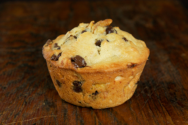 Chocolate Chip Banana Muffins A photo of a jumbo Chocolate Chip Banana Muffin displayed on a wooden board.