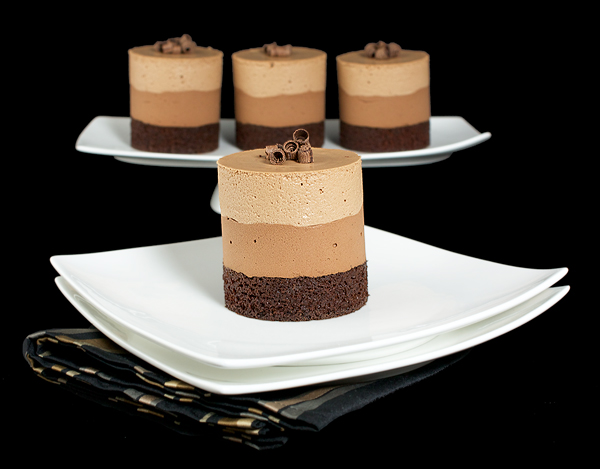chocolate cake mousse, recipe for chocolate mousse, recipes chocolate mousse A photo of 4 Triple Chocolate Mousse Cakes, one placed in front on a white dessert plate and 3 in the background on a white cake stand.