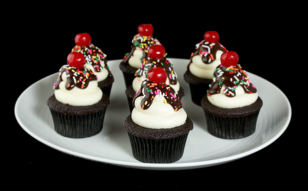 Dark Chocolate Cupcakes with Fluffy Vanilla Frosting A photo of several Dark Chocolate Cupcakes with Fluffy Vanilla Frosting decorated to look like Hot Fudge Sundaes displayed on a large white platter.