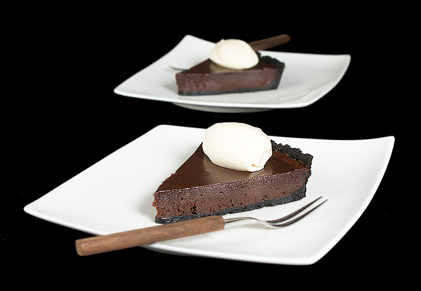 Chocolate Tart A photo of 2 slice of Chocolate Tart with Chocolate Glaze and a quenelle of Mascarpone Cream on square white dessert dishes.
