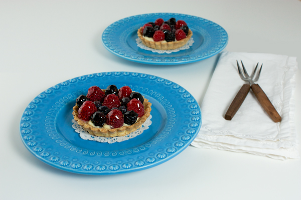 fruit tart, mini desserts, tarts, mini tarts A photo of two mini tarts on blue dessert plates with dessert forks.