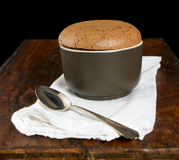 Soufflè di Nutella - Nutella Soufflé A photo of a Nutella Soufflé dessert, served in a brown ramekin and placed on a white napkin with a dessert spoon.