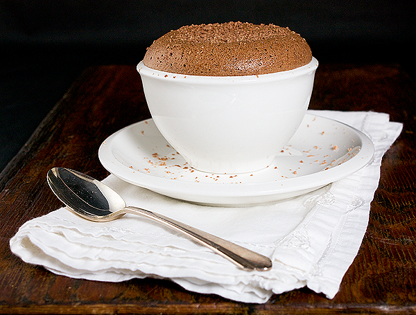 Soufflè di Nutella - Nutella Soufflé A photo of a Soufflè di Nutella - Nutella Soufflé served in a white bowl and placed on a white dessert dish with a napkin and a dessert spoon.