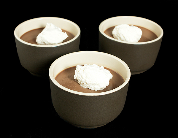 Chocolate Panna Cotta A photo of three Chocolate Panna Cotta Italian Desserts served with a dollop of Sweetened Whipped Cream in dark brown dessert cups.