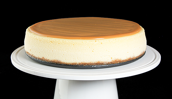 Caramel Cheesecake A photo of an Amaretto Cheesecake with Amaretto Caramel Sauce displayed on a white cake stand.