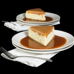 Amaretto Cheesecake with Almond Crust and Amaretto-Caramel Sauce A photo of 2 slices of Amaretto Cheesecake with Almond Crust in a pool of Amaretto-Caramel Sauce.